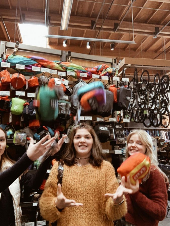 Seniors Emily Gregerson, Gabrielle Robinson, and Ruth Evilsizer toss hammocks inside an REI Co-op, feeling excited to hang their new hammock up.
