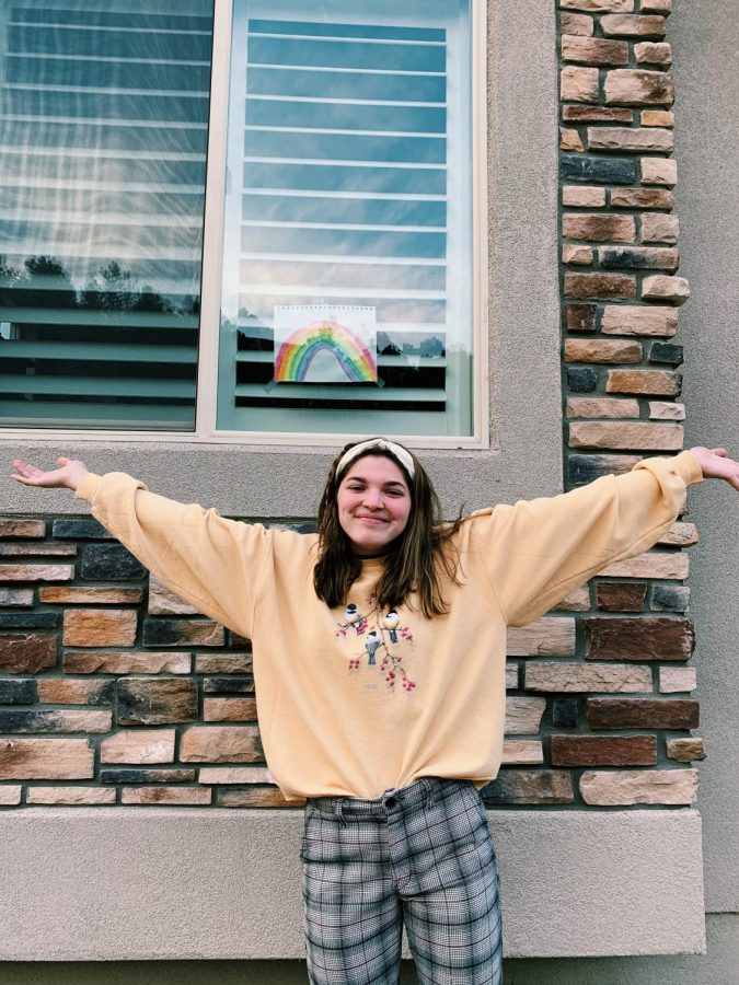 Senior Ruth Evilsizer stands outside in front of a rainbow with arms wide open for everything in store after quarantine.