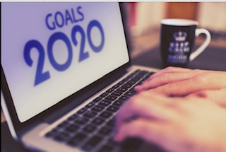 An Individuals hands typing the words GOALS 2020 in blue  into a laptops white screen. Labeled for Reuse by Creative Commons.