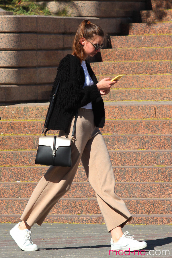 A woman goes about her day wearing a button up with dress pants and a black jacket. Labeled for Creative Commons. 