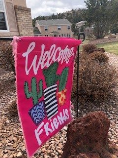 A pink welcome flag, displaying a friendly message to all who pass by, blowing in the gentle breeze which often elicit feelings of nostalgia. 