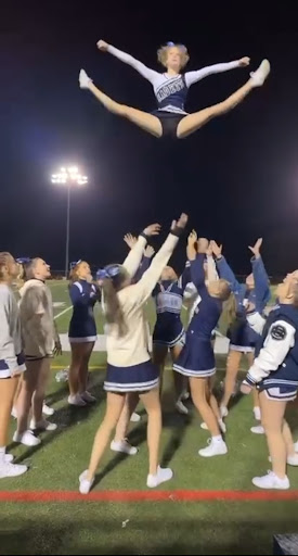 The Air Academy cheer team remarkably hits a toe touch in the air. 