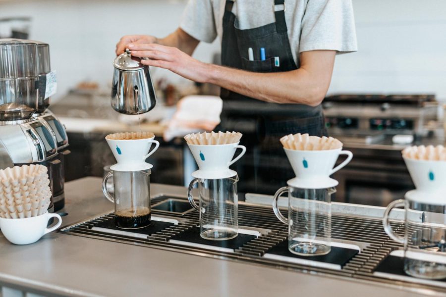 Man gently pours water into a coffee filter at his job. Labeled for reuse by Unsplash. 