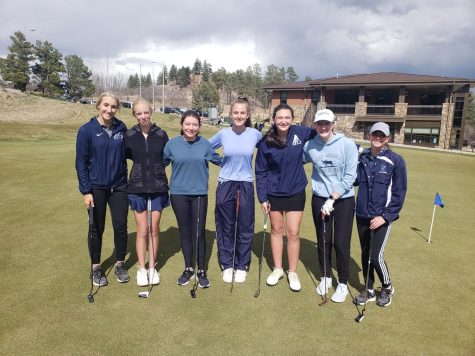 The girls golf team smile proudly as their coach, Jason Catron, takes a picture. 