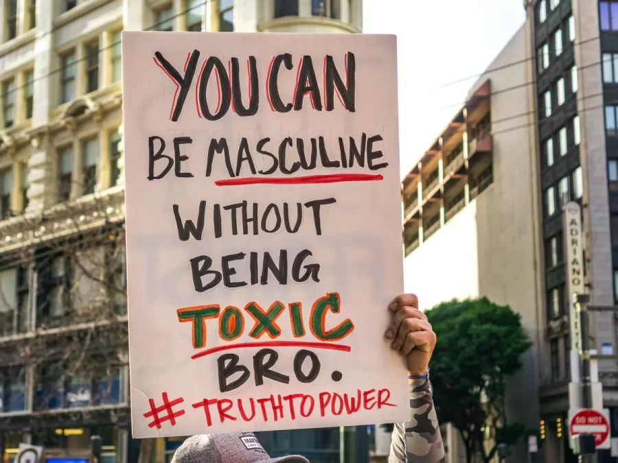 Man holds up poster at rally fighting against toxic masculnity.