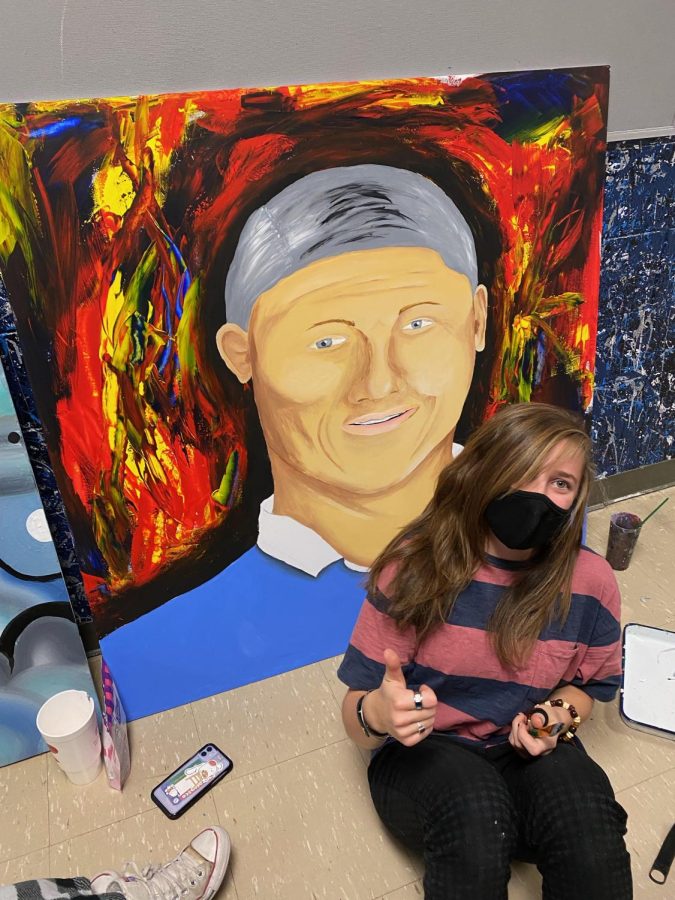 Riley Whitelaw gives a big thumbs up in front of her painting of AAHS principal, Mr. Daniel Olson! The piece was relocated  from AAHS to an art gallery exhibit in downtown Colorado Springs following her passing. 