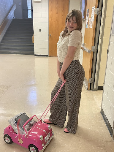 Sophmore Ella Illsley using a toy car as a backpack for anything but a backpack day.
