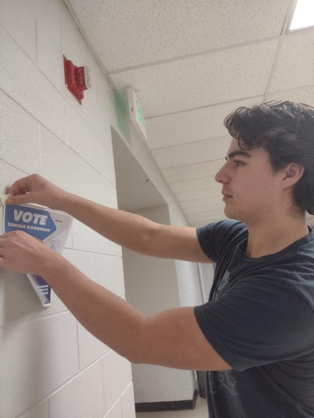 Student body president candidate Dominik Goodman hanging up promotional posters